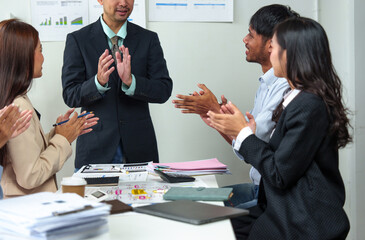 Team of cheerful Asian businessmen applauding their colleagues for their work success. Welcoming new employees Business team celebrates success together at work, clapping to congratulate each other.