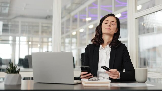 Woman sit at workplace hold credit card use phone try to pay through e-bank app experiences problems due insufficient funds, no money, insecure online payment, scam, fraud, unsuccessful transaction.