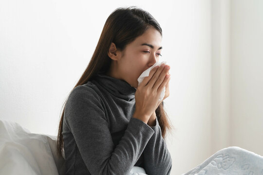 close up young girl using tissue paper stop runny nose symptom on the bed at home.