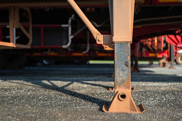 Close-up at cargo truck or trailer 's landing support legs are extended on ground, It using for support the load when the truck is parking. Transportation equipment object, selective focus.