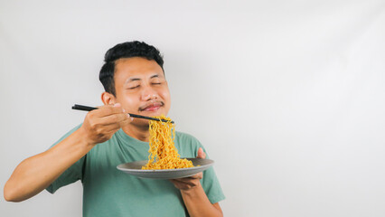 Portrait of Asian man eating delicious fried noodles using chopstick