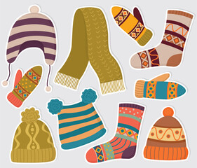 Stickers with knitted woolen clothes of various colors and patterns. Hats, mittens and socks in a flat style isolated on gray