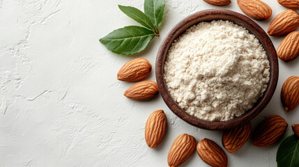 Almond flour in wooden bowl surrounded by almonds and green leaves, creating fresh and natural look. Perfect for healthy baking and cooking