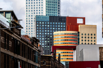 An eclectic mix of skyscrapers constructs a bustling urban skyline, showcasing a vivid blend of colors, architectural styles, and shapes against a cloudy sky in Rotterdam Netherlands