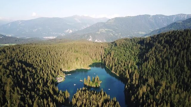 Pull out aerial shot of the stunning Caumasee, a picturesque alpine lake nestled amidst a dense forest and majestic mountains in switzerland in Graub&uuml;nden, Switzerland