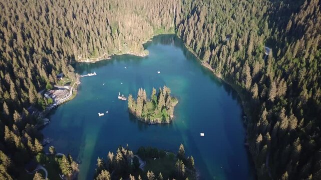 Drone close up shot capturing the Cauma swiss lake turquoise waters, dense forests, and a small island, showcasing the natural beauty of Flims, Caumasee, Graub&uuml;nden, Switzerland