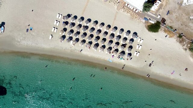 Rotating Aerial Top View over Krios Beach Straw Umbrellas in Paros, Greece