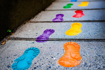 Vibrant sidewalk with colorful shoe prints in blue, orange, purple, yellow, and green, creating an artistic and playful design perfect for creative urban photography enthusiasts

