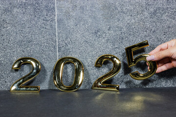 golden  numbers 2025 two thousand twenty five new year near marble stone and hand hold five 