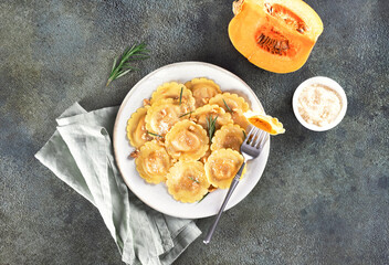 Ravioli pasta filled with pumpkin, nuts and fresh herbs on white background. 
