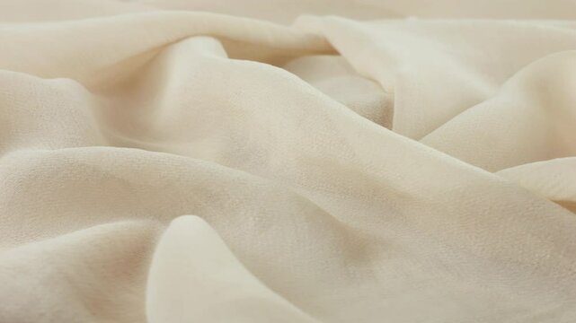 Close-up view of the soft folds of thin pink salt white color chiffon fabric on a rotating display case. Textile background with sewing accessories on the theme of fashion, design, fabrics.