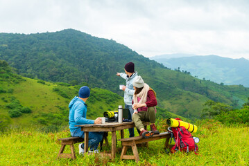 Group of Asian man and woman backpacker drinking coffee during hiking on the mountain. People enjoy outdoor active lifestyle travel nature hiking and camping at forest mountain on holiday vacation.
