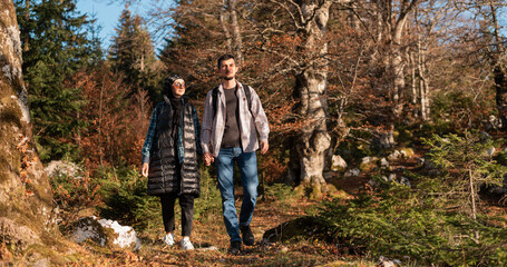Obraz premium A happy couple traveler walking together with holding hands in the autumn forest during the hike, adventure travel.