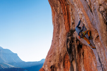 male climber. Athletic man climbing up an overhanging rock with a rope. rock climbing in Turkey.