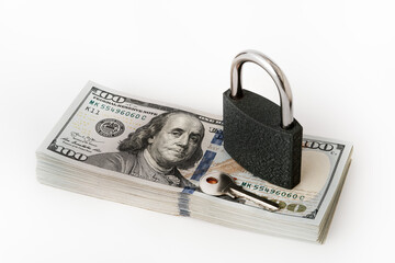 A stack of U.S. one-hundred-dollar bills. Financial security, wealth protection, and money management. The padlock on the cash with a silver key. Concepts in banking, investments, personal finance. 