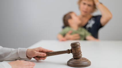 A judge hits a gavel against the backdrop of an elderly woman holding a child. 
