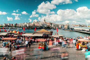 Eminonu, Istanbul. People walking on Eminonu beach. Galata Tower, fish and bread boats in the...