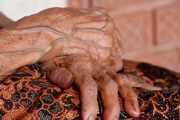 Close up an old woman hand with blood vessels on hand's skin with dark background 