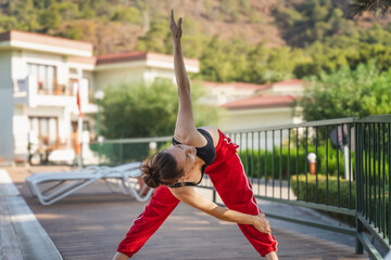 Young woman doing warm-up or stretching exercises in swimming pool area of ​​residential building