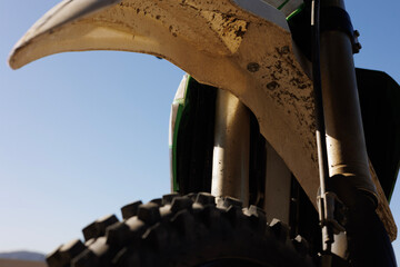 Close-up of a dirt bike's front tire, looking up towards the tire guard and handlebars, showcasing...
