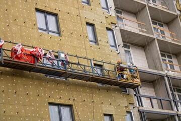 A man works on scaffolding located on the side of a building