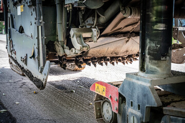 Asphalt Milling Machine Removing Old Asphalt Layer on Road. Closeup. Asphalt milling.
