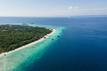 A serene lagoon showcases crystal-clear blue waters, dotted with wooden piers and a small boat, inviting exploration in a tropical setting.