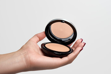Woman`s hands holding cream foundation  on a white background