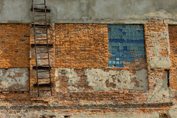 Old brick wall with ladder and blue and red tiles. Abstract background.