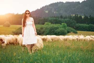 Woman kneeling beside sheep in countryside