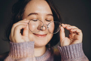 Beautiful young woman wearing eyeglasses with eyes closed, close up.