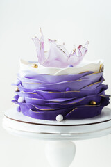 Beautiful cake with violet mastic frosting decorated with caramel transparent vase on top....