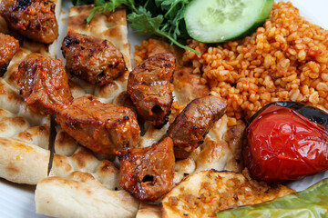 Turkish kebab lamb meat on skewer.
with vegetables and rice on a serving plate