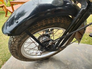 Close-up of a classic motorcycle wheel featuring shiny spokes, a vintage rim, and rugged tire texture. Perfect for retro, automotive, and mechanical themes, highlighting timeless design 