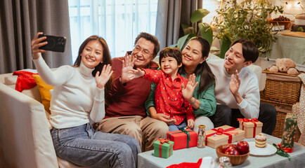 parenthood, family, party, enjoyment, greeting, xmas, present, celebration, christmas eve, happiness. A family is sitting on a couch and taking a picture of themselves. Scene is happy and festive.