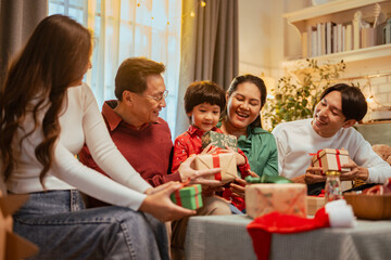 presents, parenthood, family, party, celebrate, xmas, celebration, gift, christmas, parents. A family of four is sitting on a couch, opening presents and laughing. Scene is joyful and festive.