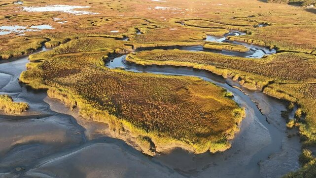 Sunrise aerial of salt marshes at Sandy Neck Beach, Massachusetts, with golden light reflecting on tidal pools