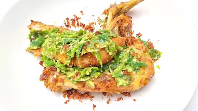 Ayam Penyet Cabe Ijo is a flavorful dish with fried chicken covered in crushed green chili peppers.