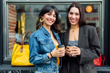 Two young women drinking coffee on the street