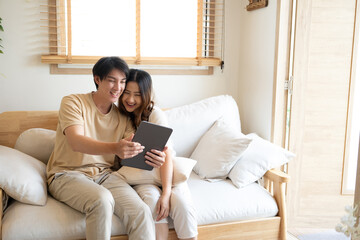 Cheerful young couple relaxing together at home and watching something funny on digital tablet