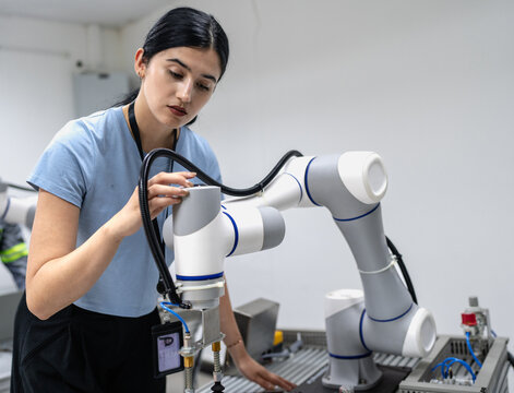 Hispanic engineer woman working on AI technology in robotics electronics engineering laboratory. University students' research project is programming robot machine with intelligent mechanical control