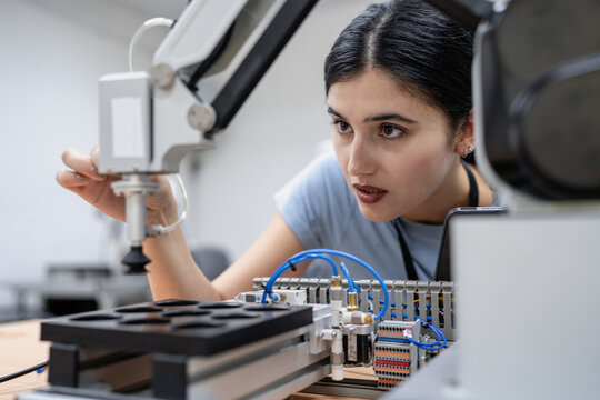 Hispanic engineer woman working on AI technology in robotics electronics engineering laboratory. University students' research project is programming robot machine with intelligent mechanical control - Powered by Adobe
