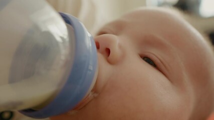 Portrait of infant baby drinking powdered milk in a bottle. Baby face being fed. Newborn and family content.