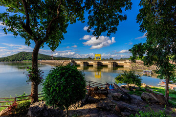 Natural background of clear sky, amidst the blue sky at the viewpoint, there are trees, sun, water retention dam, a nature stop for tourists.