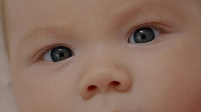Extreme close up of newborn infant baby face awake calm and innocent looking up. Amazed little infancy child eyes showing emotion.