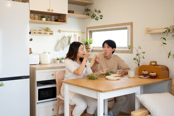 Happy asian couple enjoying enjoying a nutritious meal in their home kitchen