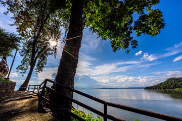 Natural background of clear sky, amidst the blue sky at the viewpoint, there are trees, sun, water retention dam, a nature stop for tourists.