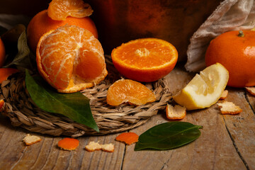 Close-up of cut oranges, tangerines and lemons with green leaves on a wooden table, horizontal with copy space