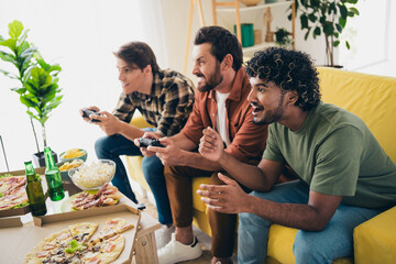Photo of company three friends sit couch play games hang out weekend modern interior apartment indoors