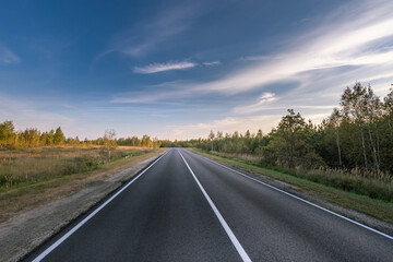 Fototapeta premium A long, empty road with a blue sky in the background
